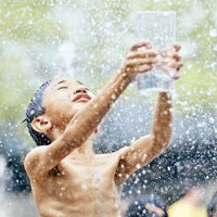 小童在北京三里屯噴泉中戲水納涼。（中新社圖片）