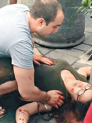 中刀婦人倒臥地上，其法籍丈夫在旁照顧。（互聯網圖片）