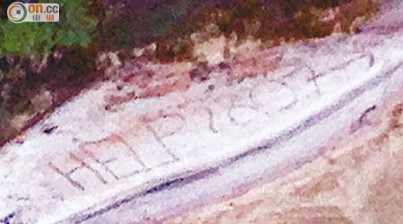 基斯在沙灘上寫上「救命」字樣。