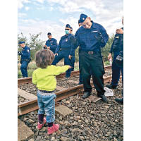 一名難民孩童（左）請匈牙利警員吃餅。（互聯網圖片）