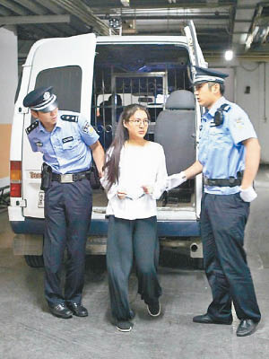 郭美美被扣手銬走下囚車，由兩名法警押往法庭。