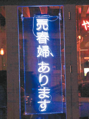 霓虹燈廣告牌上以日文顯示「這裏有賣春婦」。