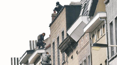 大批比利時特警包圍並爬入一幢建築物。