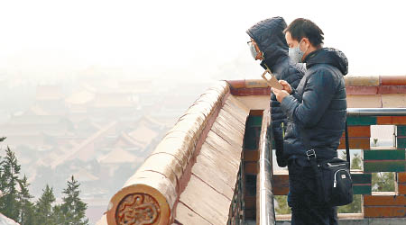 戴口罩的遊客在景山上觀看北京霧霾景貌。（互聯網圖片）