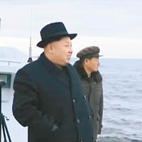 金正恩（左）在艦上視察試射，展露笑容。