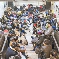 大批滯留旅客在車站梯間休息。（中新社圖片）
