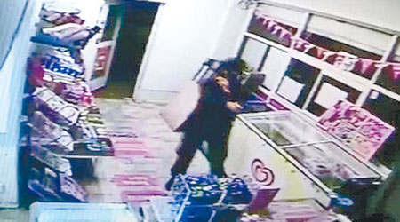 一名蒙面賊人突闖入店內打劫，隔着櫃台舉槍指嚇她。（互聯網圖片）