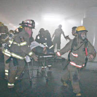 消防員從充滿煙霧的地庫中救出傷者。（互聯網圖片）