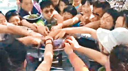 中國遊客如餓鬼般伸出手臂搶水果。（電視畫面）