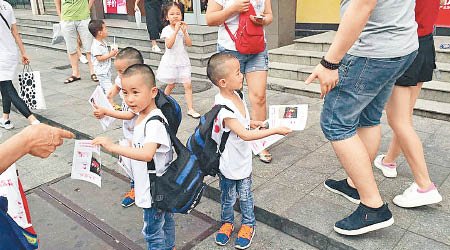 三胞胎兄弟在東門街頭向途人派傳單。