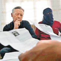 蒙面的IS變節者向英國記者（左）解讀機密文件。