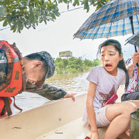 有救生艇在洪水中被樹枝卡住，艇上的女孩受驚。（中新社圖片）