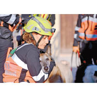 一名搜救人員緊抱受驚的狗隻。