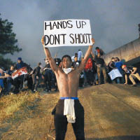 示威者舉標語，批評警方對舉高手的黑人開槍。（Getty Image圖片）