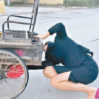 女子為老翁修理三輪車。