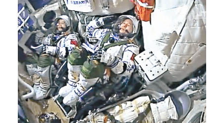 兩名太空人在太空艙內向地面控制室敬禮致意。（中新社圖片）