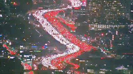 感恩節來臨，美國民眾紛出門旅行，洛杉磯一條高速公路出現長長的車龍。（電視畫面）