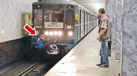 一名男子緊抓行駛中的地鐵列車（箭嘴示）。（互聯網圖片）