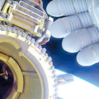 太空人用手遮擋光點。（NASA圖片）