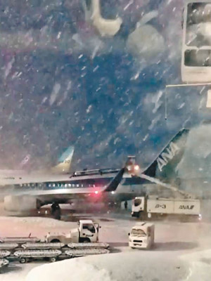 新千歲機場的跑道因大雪而封閉，當局更為飛機除雪。（電視畫面）