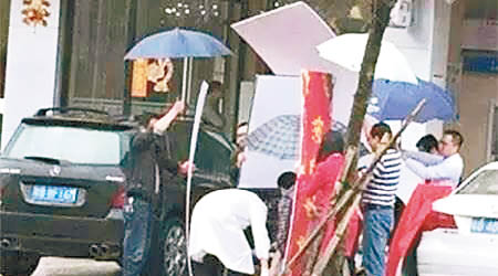 一家公司的員工為譚婦遮風擋雨。（互聯網圖片）