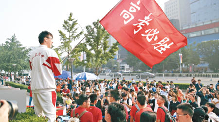 北京一個考場外，有學生揮舞「高考必勝」的旗幟，為同學們打氣。（中新社圖片）