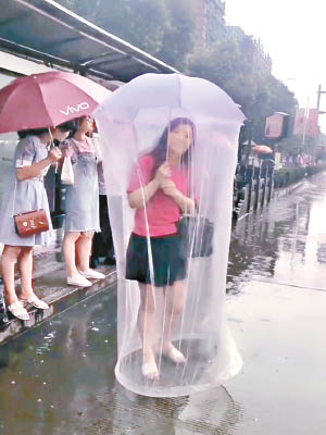 女子撐着的雨傘增設一層薄紗，被網民笑指像「大型避孕套」。（互聯網圖片）