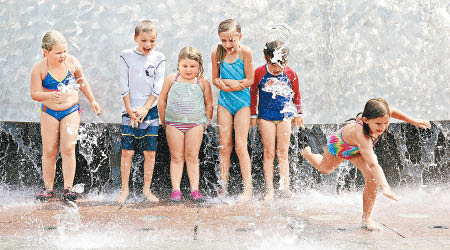 大批小孩在噴水池戲水降溫。