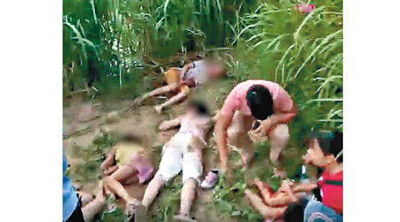 多名學童倒臥在河邊石灘上。