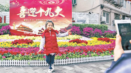 民眾在北京的十九大布置花壇前留影。（中新社圖片）