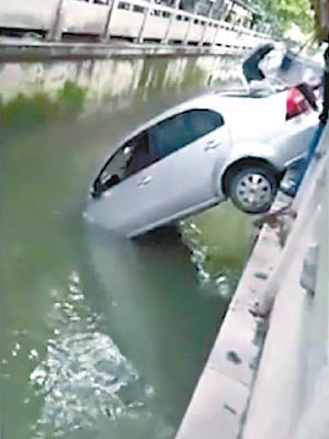 車頭直插水中，車身卡在岸邊。