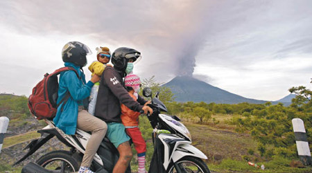 阿貢火山噴發，民眾騎電單車撤離。（美聯社圖片）