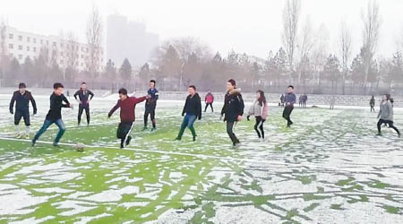 大批學生在鋪滿雪的草地上踢足球。（互聯網圖片）