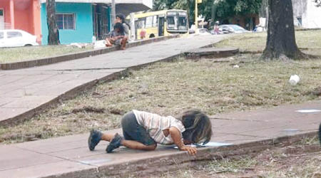 小女孩趴在地上啜飲污水。（互聯網圖片）