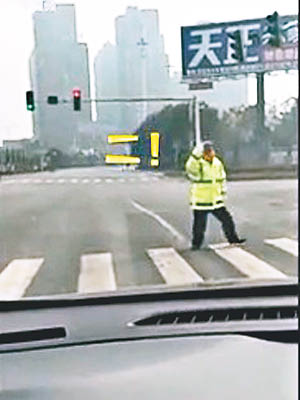 交警在紅綠燈前向司機做數字手勢。