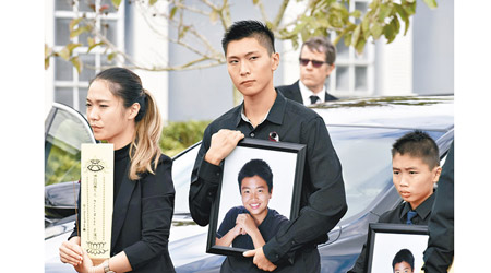 家人捧着王孟杰的遺照。（美聯社圖片）
