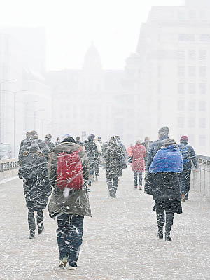 倫敦民眾在風雪中步行上班。（美聯社圖片）
