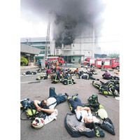 與大火搏鬥多時，一眾消防員累癱在地上。（中時電子報圖片）