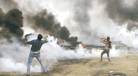 巴勒斯坦示威者把催淚彈的氣罐掟向以軍。（美聯社圖片）
