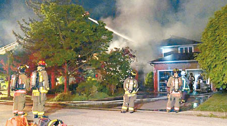 消防員到場灌救，起火的住宅被燒通頂。（中新社圖片）