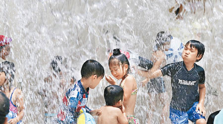 東京一班小孩在水中玩耍消暑。（美聯社圖片）