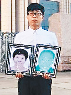 廖海軍在法院外手持父母的遺照。（互聯網圖片）