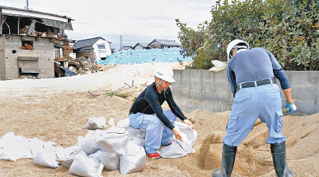 工人在岡山放置沙包防範水浸。（美聯社圖片）