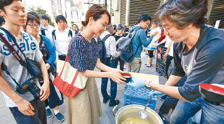 札幌有餐廳職員向市民發放湯水。（美聯社圖片）