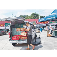 水產市場的商販將大量印有「陽澄湖大閘蟹」字樣的禮品盒搬上車運往出售。