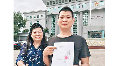 黄志明（右）與其二姐展示獲判無罪的判決書。（互聯網圖片）