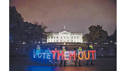 示威者在白宮前高舉「用選票趕走他們」的燈牌。（美聯社圖片）