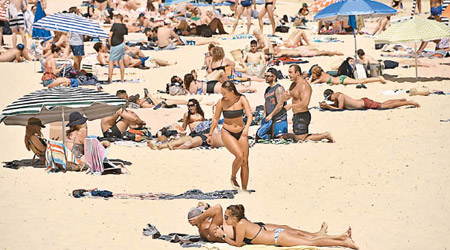 澳洲連日高溫，民眾湧往沙灘曬太陽。