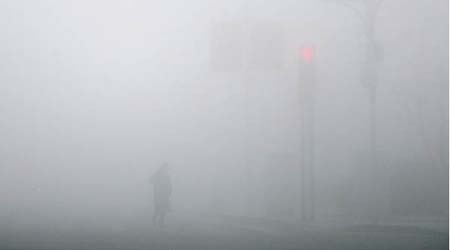 天津市民在霧霾籠罩中的街頭行走。（中新社圖片）