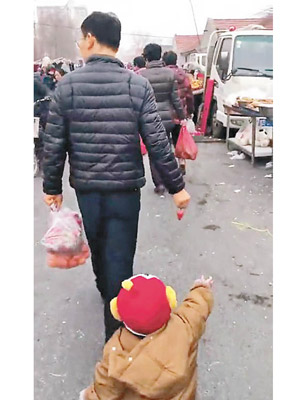 小孩伸手試圖抓着父親手中的士多啤梨。（互聯網圖片）